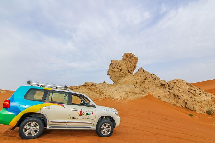 Experience the stunning desert landscape as a 4x4 takes you to unique rock formations. Discover the beauty of Fossil Rock and Camel Rock amidst golden sand dunes.